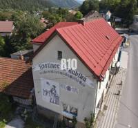 Budova hostince v Belej s červenou střechou a vyobrazením na stěně.