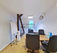 Kanceláře s podlahou s dřevěným dekorem, stůl, židle, flipchart, voda na stole.