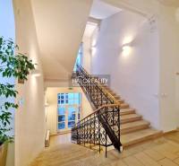 Světlé schodiště s ozdobným zábradlím, vedoucí do kanceláří.