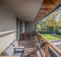 Balkon 2-pokojového bytu v Tatranské Lomnici s podlahou s dřevěným dekorem a zahradním nábytkem.