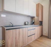 Kuchyně v 2-pokojovém bytě s podlahou s dřevěným dekorem a světlou linkou.