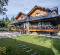 Dvoupatrový dům s dřevěnými prvky a zeleným trávníkem v Tatranské Lomnici.