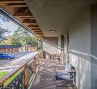 Balkon 2-pokojového bytu v Tatranské Lomnici s dřevěným dekorem a venkovním posezením.