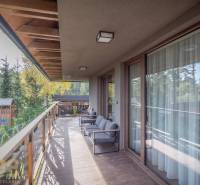 Balkon 2pokojového bytu v Tatranské Lomnici s podlahou s dřevěným dekorem a výhledem na zeleň.