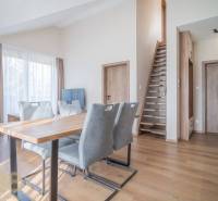 Obývací pokoj s jídelním stolem a schodištěm v 2pokojovém bytě, podlaha s dřevěným dekorem.