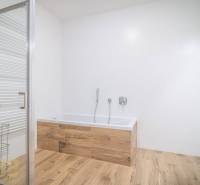 Koupelna s vanou a podlahou s dřevěným dekorem v 2-pokojovém bytě.