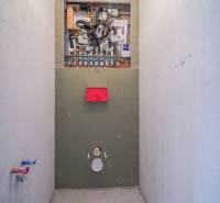 Instalace sanitárního zařízení v 2-pokojovém bytě s podlahou s dřevěným dekorem.