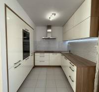 Kuchyně ve 4-pokojovém bytě se světlými skříňkami a dlažbou na podlaze.