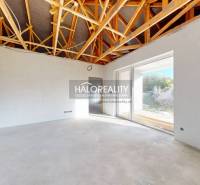 Interiér rodinného domu s odkrytým stropem a velkými prosklenými dveřmi.