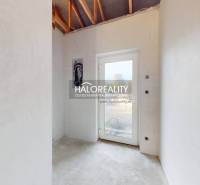 Světlá místnost v rodinném domě s betonovou podlahou a skleněnými dveřmi.