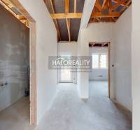 Interiér rodinného domu s pohledem na přechodové chodby a odkrytou střešní konstrukci.