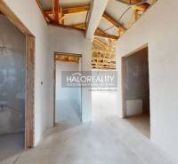 Nedokončený interiér rodinného domu s dřevěnou konstrukcí střechy a otevřenými místnostmi.