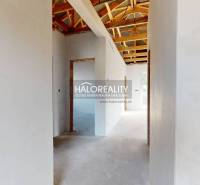 Interiér rodinného domu se střešní konstrukcí a bílými omítnutými stěnami.