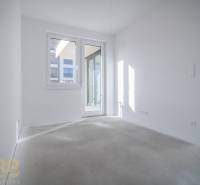 Světlý pokoj s bílými stěnami a velkými okny ve 3-pokojovém bytě.