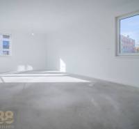 Prázdný pokoj v 3-pokojovém bytě se světlými stěnami a velkými okny, bez podlahy s dřevěným dekorem.