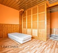 Interiér rodinného domu s podlahou s dřevěným dekorem, matrací a vestavěnou skříní.