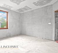 Nevyhotovená místnost v rodinném domě s betonovou podlahou a velkým oknem.