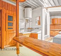 Kuchyně v rodinném domě s dřevěným obkladem a praktickým vybavením.