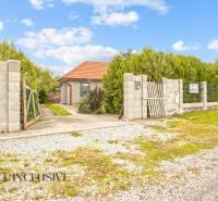 Rodinný dům v Bátorových Kosihách, obklopený zelení, s cestičkou vedoucí k bráně.