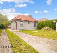 Rodinný dům v Bátorových Kosihách, s trávníkem, betonovým chodníkem a červenou střechou.