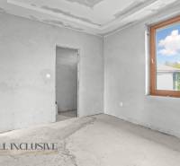 Interiér rodinného domu s nedokončenými stěnami a velkým oknem.