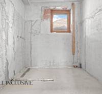 Rekonstrukce koupelny v rodinném domě, stěny z neomítnutého betonu, jediné malé okno.