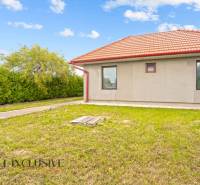 Rodinný dům v Bátorových Kosihách s červenou střechou obklopený zeleným trávníkem a keři.