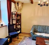 Obchodní prostory se zelenou sedačkou, poličkami a podlahou s dřevěným dekorem.