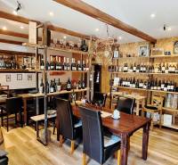 Interiér obchodních prostor s podlahou s dřevěným dekorem, plný lahví vína a dřevěných prvků.