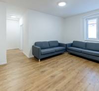 Obývací pokoj s modrou pohovkou a podlahou s dřevěným dekorem ve 3-pokojovém bytě.