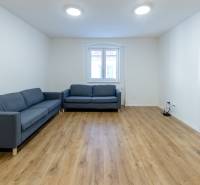 Obývací pokoj v 3-pokojovém bytě s pohovkou a podlahou s dřevěným dekorem.