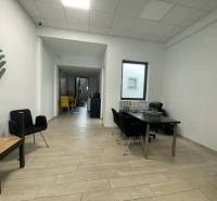 Obchodní prostory s podlahou s dřevěným dekorem, minimalistický nábytek a výrazné židle.