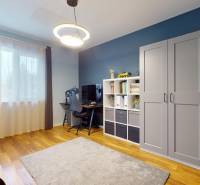 Pokoj v rodinném domě s psacím stolem, poličkou a podlahou s dřevěným dekorem.