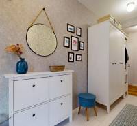 Chodba v rodinném domě se zrcadlem, dekoracemi a úložným prostorem.