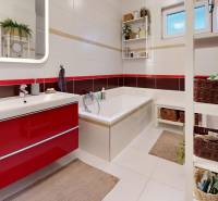 Koupelna v rodinném domě s vanou, umyvadlem a úložnými koši.