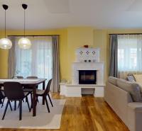 Obývací pokoj s krbem, jídelním stolem a podlahou s dřevěným dekorem v rodinném domě.