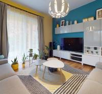 Obývací pokoj v rodinném domě s barevnými stěnami, podlahou s dřevěným dekorem a pokojovými rostlinami.