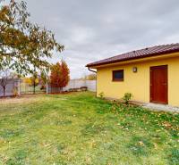 Zahrada u rodinného domu na Jetelové ulici v Iži s dřevěným přístřeškem na dvoře.