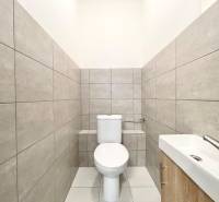 Toaleta s umyvadlem a šedým obkladem v interiéru kanceláří.