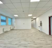 Kanceláře s podlahou s dřevěným dekorem, bílými stěnami a velkými okny.