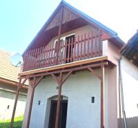 Chata v Hontianských Trsťanech s dřevěným balkonem a satelitní anténou.