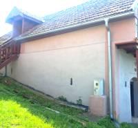 Chata v Hontianských Trsťanech s venkovním schodištěm, trávníkem a satelitní parabolou.