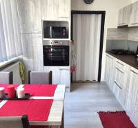 Kuchyně s jídelním stolem, bílými žaluziemi a kuchyňskou linkou v 2-pokojovém bytě.