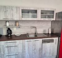 Kuchyně v 2-pokojovém bytě s červenou lednicí a podlahou s dřevěným dekorem.