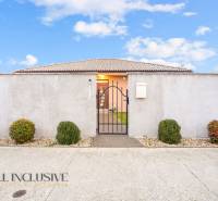 Rodinný dům v Gabčíkovu s plotem, bránou a ozdobnými keři.