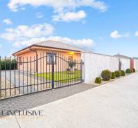 Rodinný dům v Gabčíkovu s kovanou bránou, upravenou zahradou a parkovací plochou.