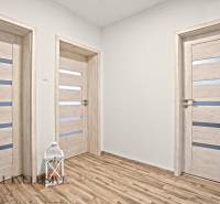 Interiér rodinného domu s podlahou s dřevěným dekorem a bílými dveřmi.