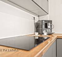 Kuchyně v rodinném domě s kávovarem a varnou deskou na dřevěném dekoru.