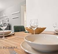 Jídelní stůl se sklenicemi, talíři a miskou v interiéru rodinného domu.