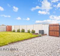 Zahrada u rodinného domu v Gabčíkově s trávníkem, kamínky a dřevěným plotem.